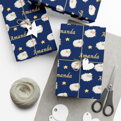 Personalized baby wrapping paper with navy blue background featuring watercolor sheep, stars, and a custom name printed throughout the design.