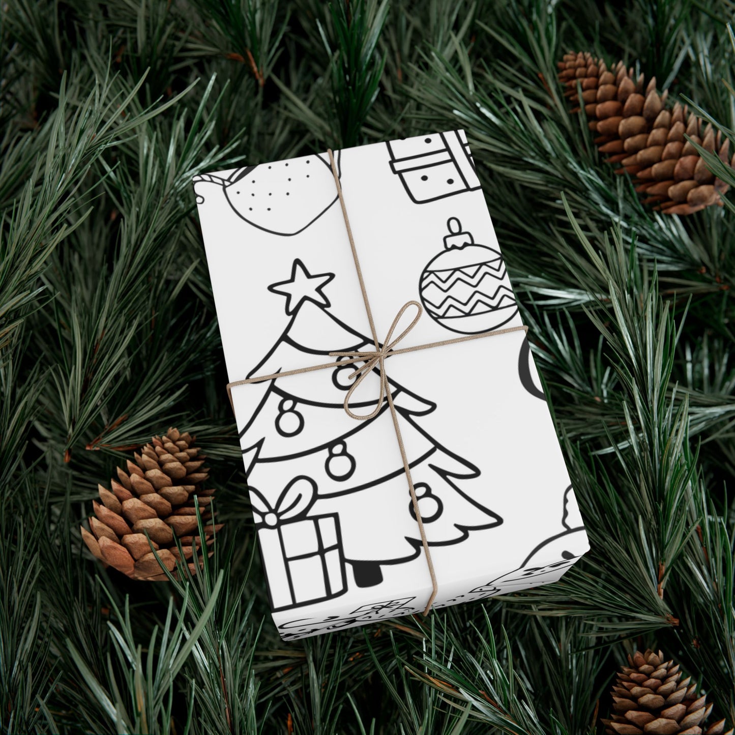 Gift wrapped in black and white patterned paper with Christmas elements made to be colored in, tied with brown string, on green pine needles with pine cones.