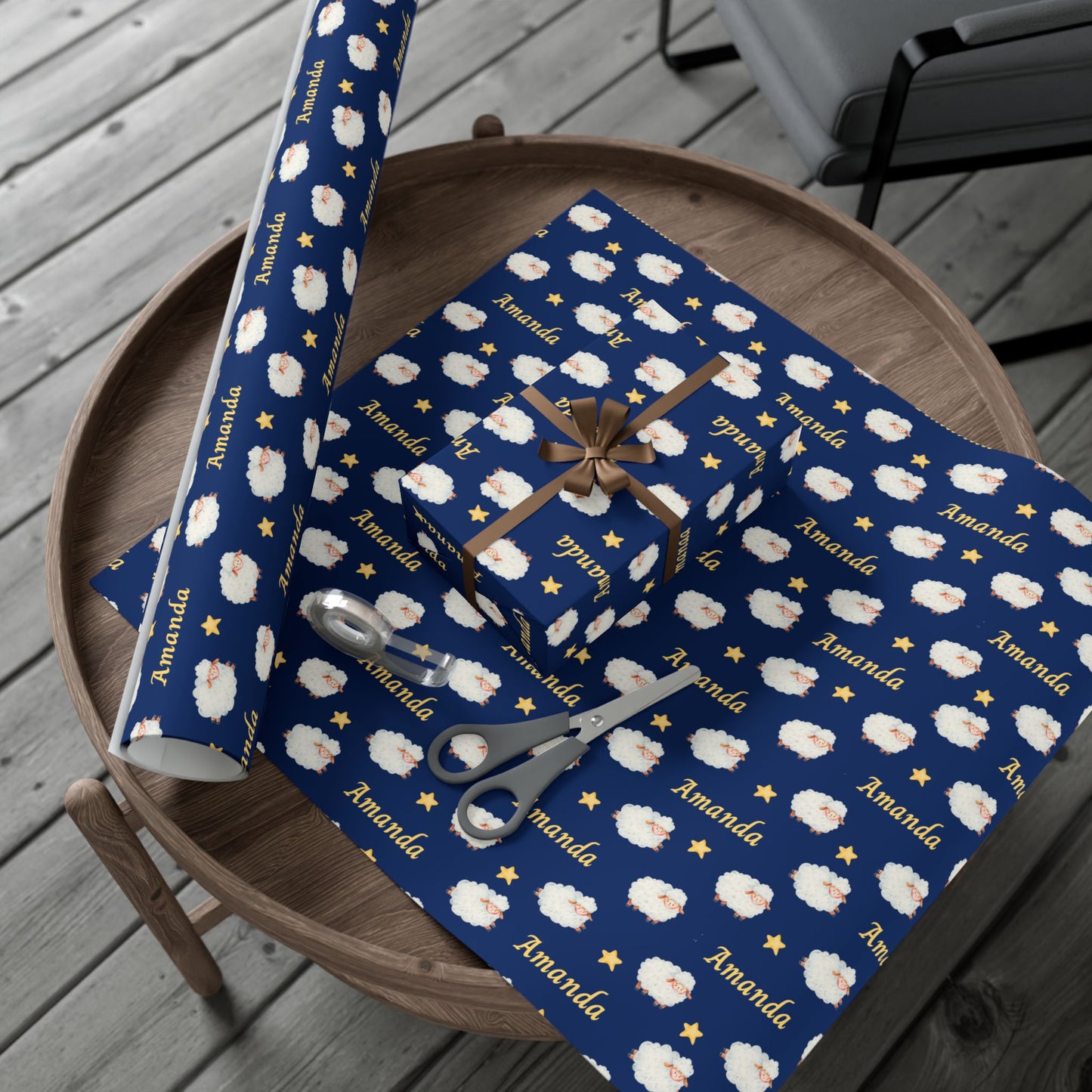 Blue gift wrap with white sheep pattern and 'Amanda' branding on a wooden surface.