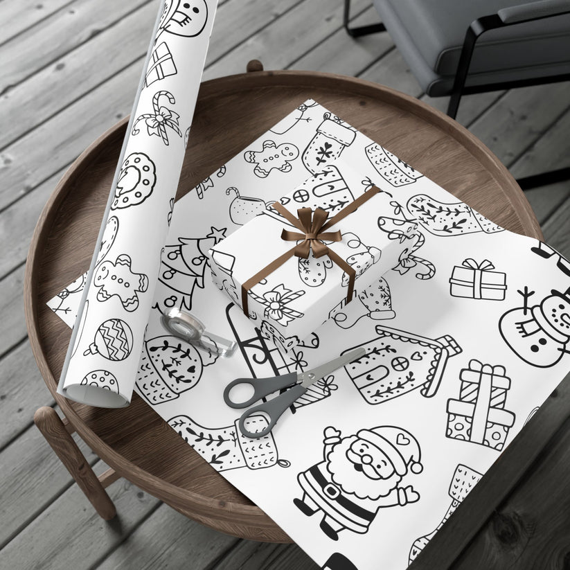 Rolls of black and white Christmas-themed gift wrap made to be colored in, on a wooden tray.