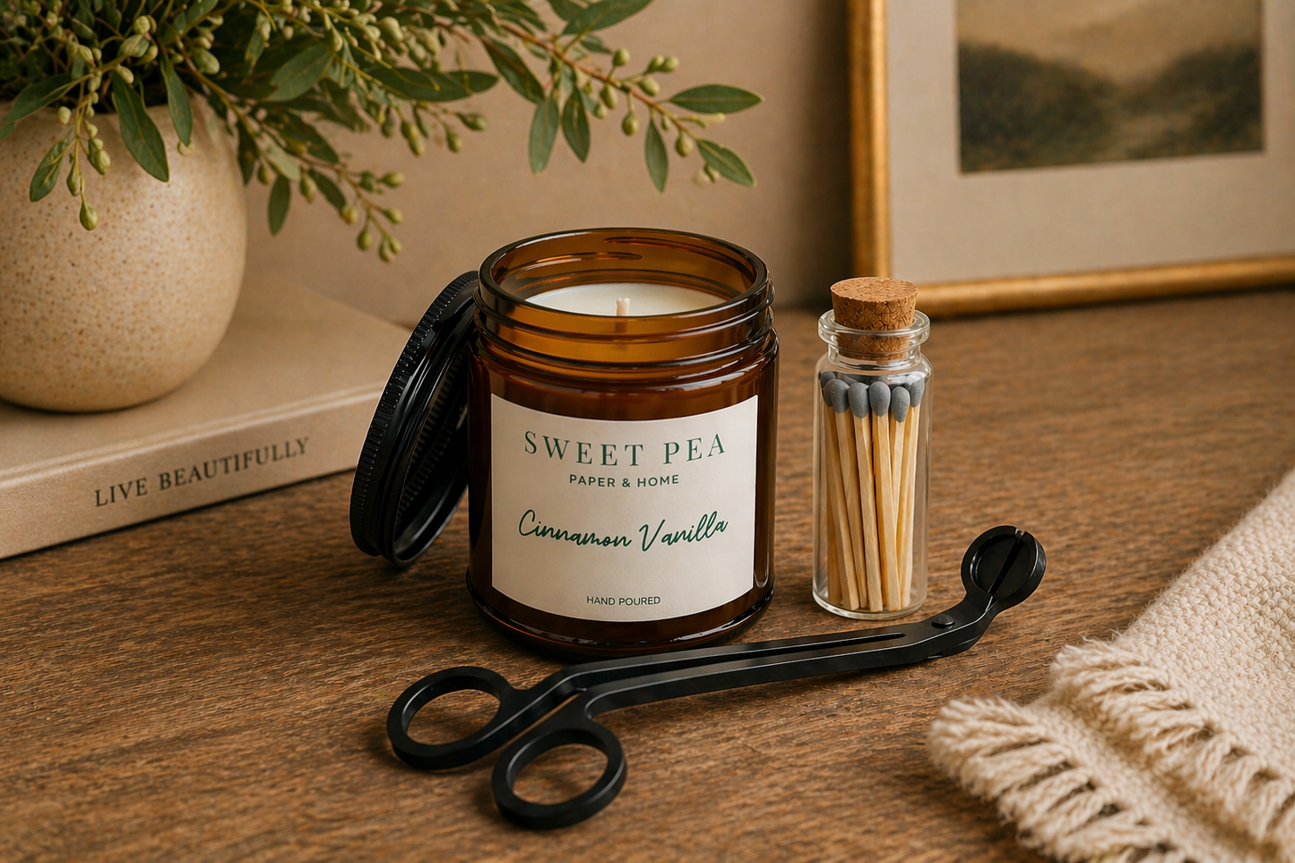 Candle labeled 'Sweet Pea' by Paper & Home on a wooden surface with matches and scissors.