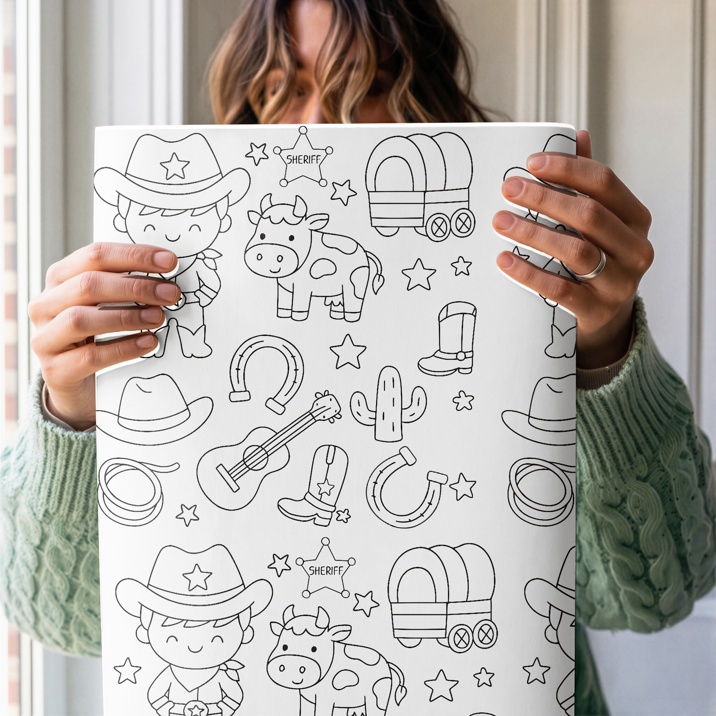 Person holding a coloring wrapping paper with western-themed illustrations