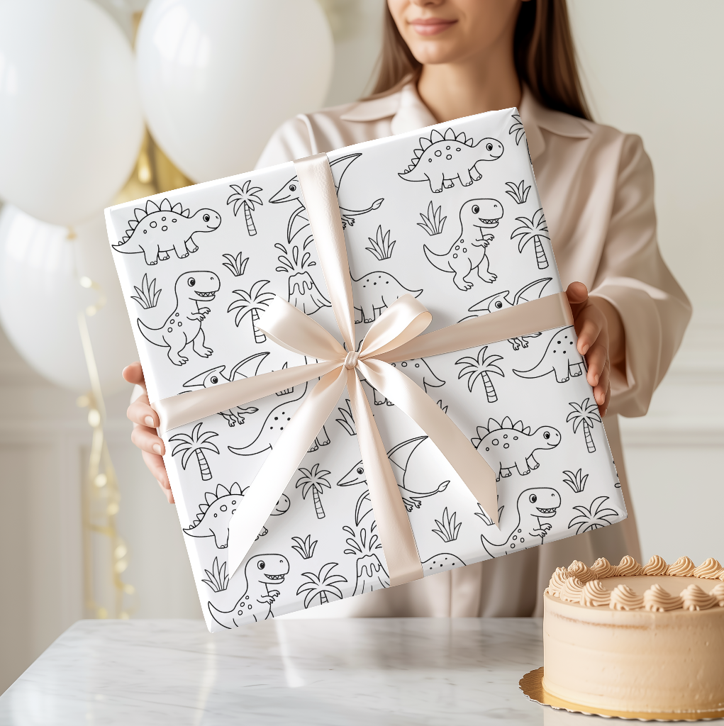 Person holding two wrapped presents with dinosaur patterns and a cake on a table.