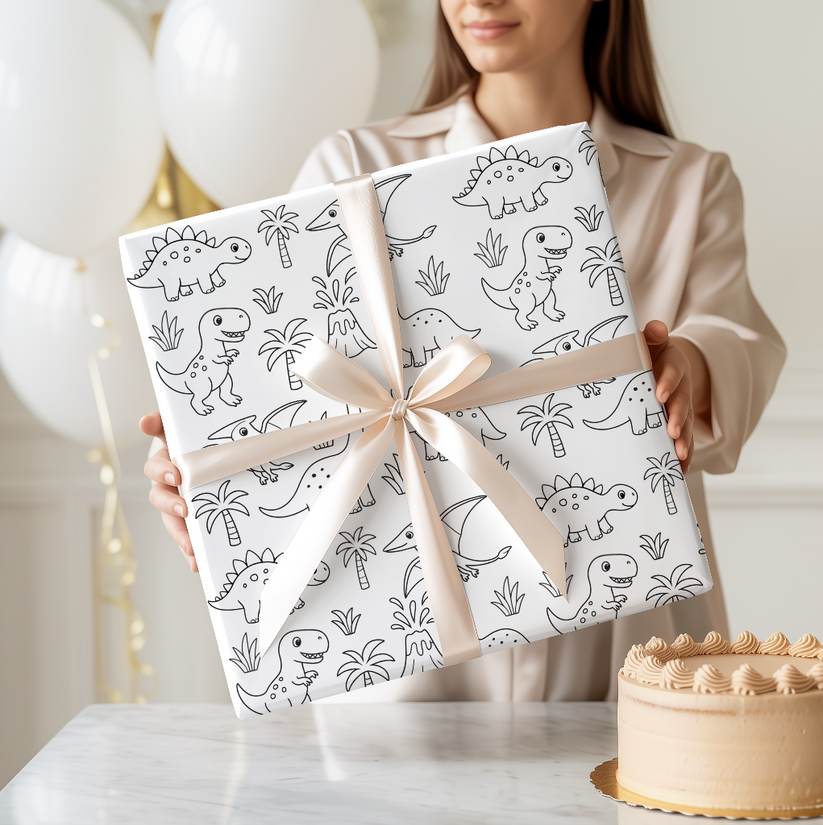 Person holding two wrapped presents with dinosaur patterns and a cake on a table.