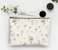 Floral-patterned pouch with cosmetic items on a light background