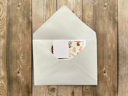 White envelope with a floral card on a wooden surface