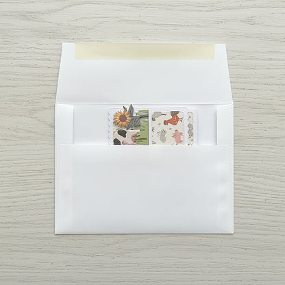 Folded flat pop-up card with a farm theme shown in an envelope on a wooden background