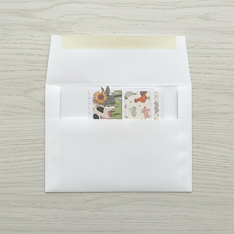 Folded flat pop-up card with a farm theme shown in an envelope on a wooden background