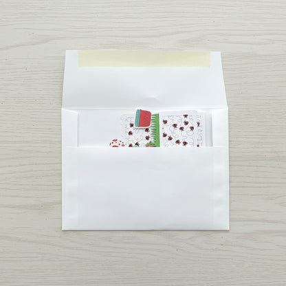 White envelope with a small card featuring a red flower design on a black marble surface