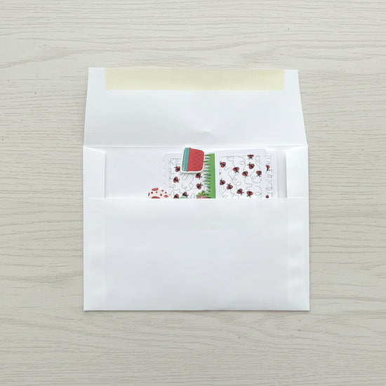 White envelope with a small card featuring a red flower design on a black marble surface