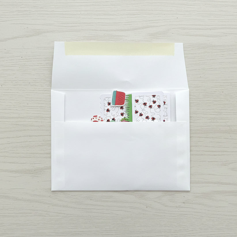White envelope with a small card featuring a red flower design on a black marble surface
