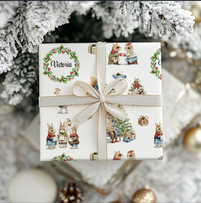 Gift box under a Christmas tree with festive, watercolor, hand illustrated images of woodland animals dressed for Christmas in Victorian outfits.  A wreath surrounds personalization of "Victoria".