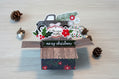 Christmas-themed card with a truck and festive elements on a wooden surface.