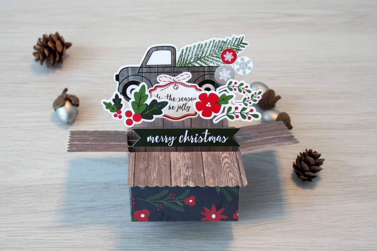 Christmas-themed card with a truck and festive elements on a wooden surface.