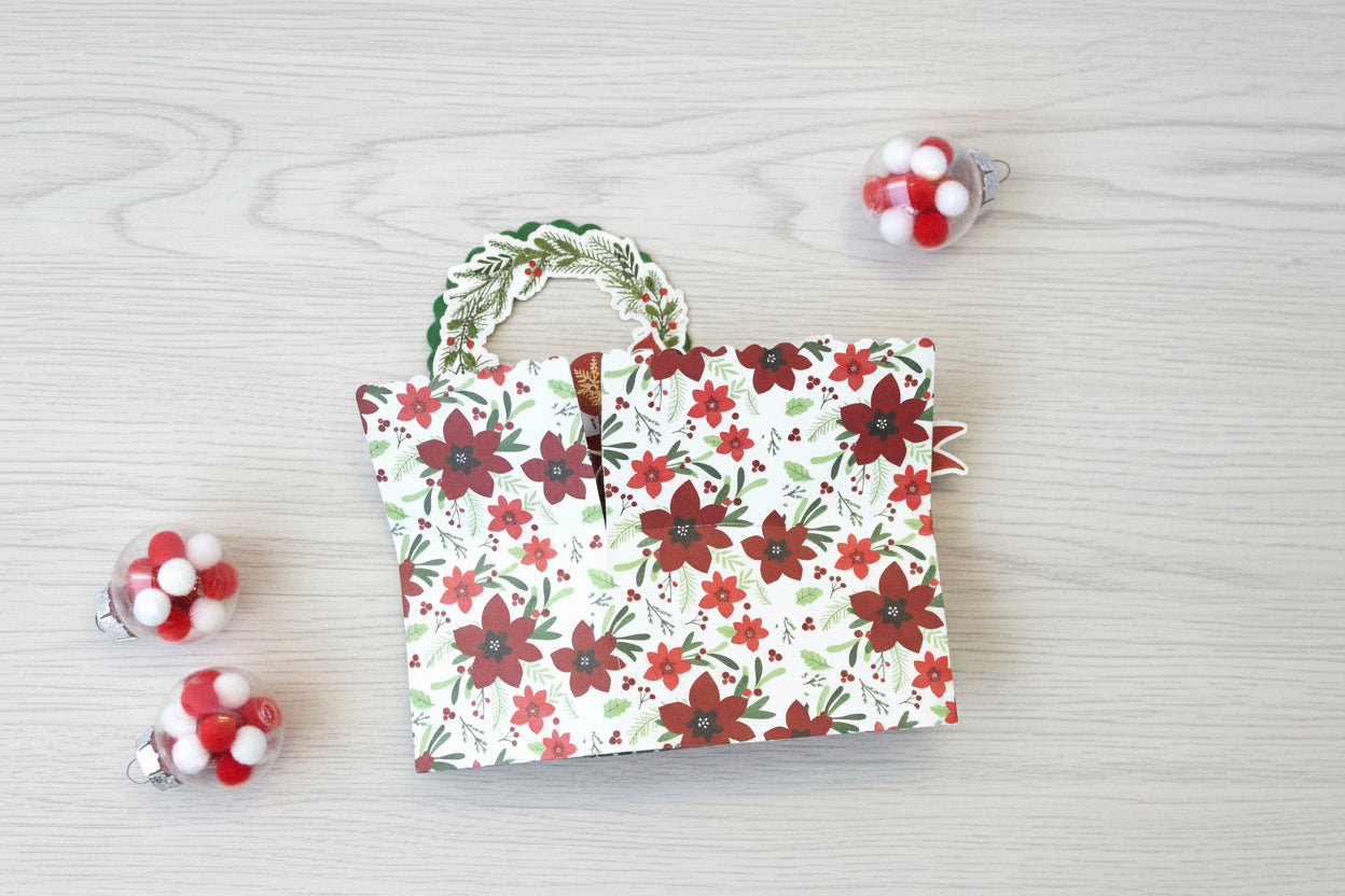 folded pop-up Christmas card with poinsettia pattern on the outside.