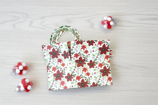 folded pop-up Christmas card with poinsettia pattern on the outside.