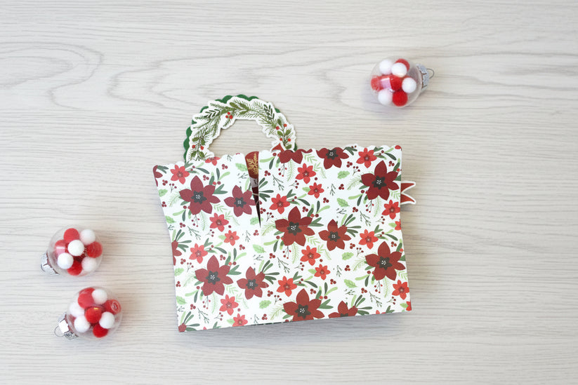 folded pop-up Christmas card with poinsettia pattern on the outside.