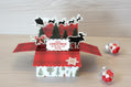 Christmas-themed card with reindeer, trees, and a moose on a wooden surface.