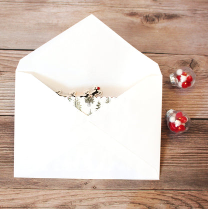 White envelope with a Christmas design on a wooden surface with candy hearts.