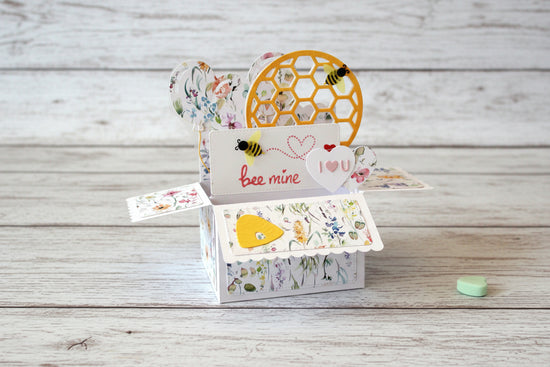 Pop-up Valentine's Day card with honeycomb design and heart-shaped elements on a wooden surface.
