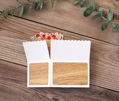 Wooden sample cards with a decorative flower arrangement on a wooden surface