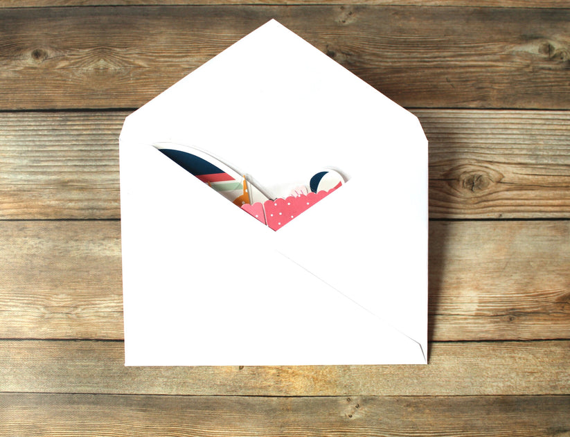 White envelope with a colorful letter inside on a wooden surface