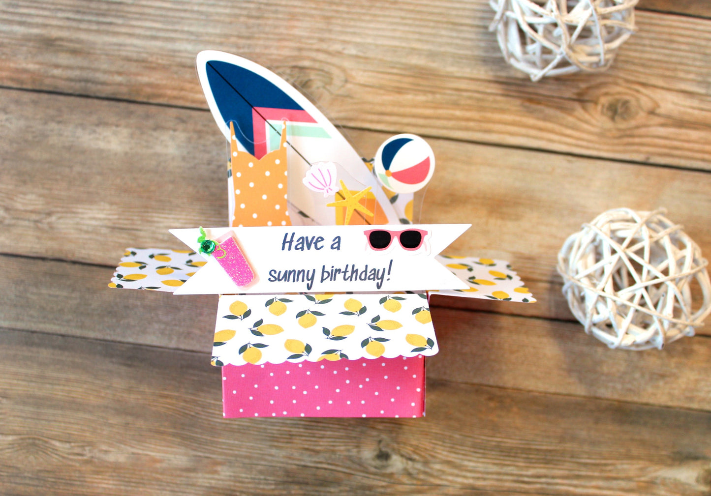 Colorful gift box with 'Have a sunny birthday!' message on a wooden surface