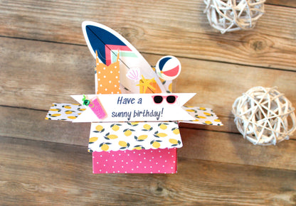 Colorful gift box with 'Have a sunny birthday!' message on a wooden surface