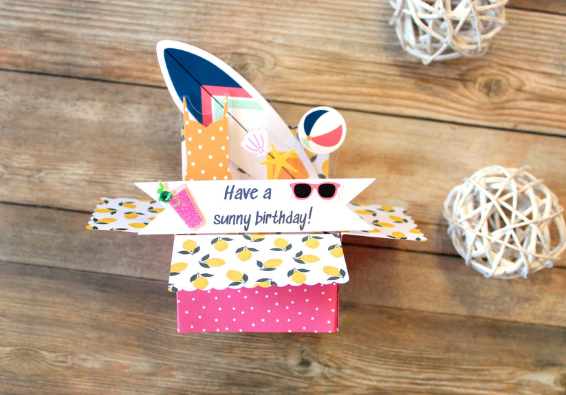 Colorful gift box with 'Have a sunny birthday!' message on a wooden surface