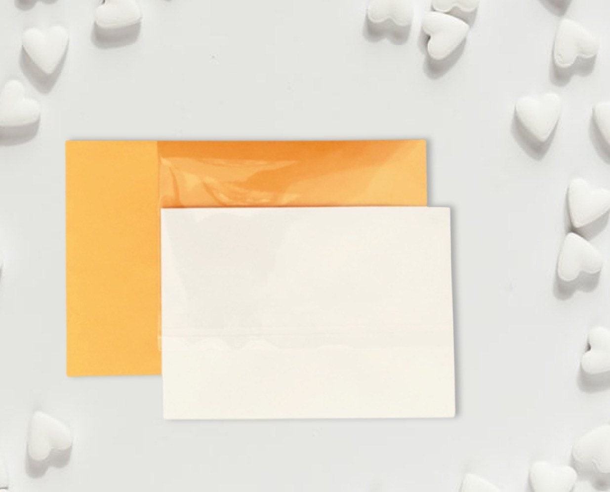 Two square cards, one orange and one white, on a light gray background with white heart shapes.