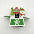 Christmas-themed pop-up card with snowman, trees, and house on a white background.