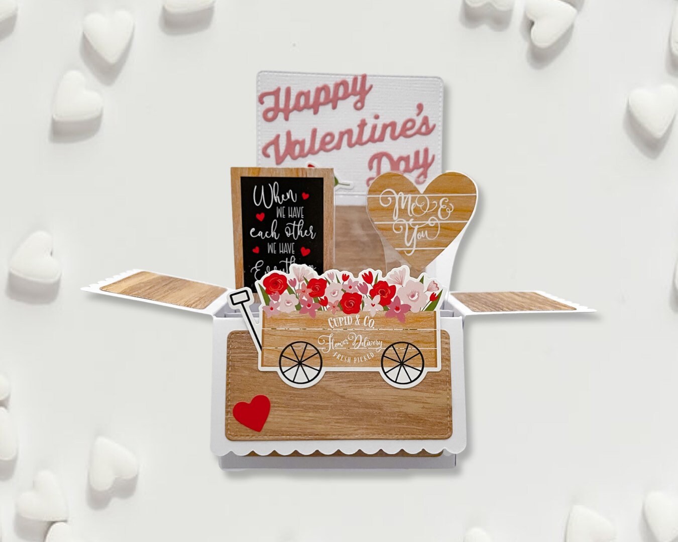 Valentine's Day card with a wooden cart, flowers, and decorative text on a white background.