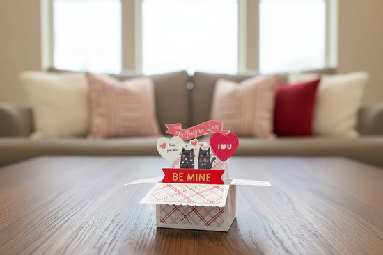 Valentine's Day card with two cats and decorative elements on a wooden floor.