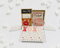 Valentine's Day card with kissing booth design on a white background with heart decorations.