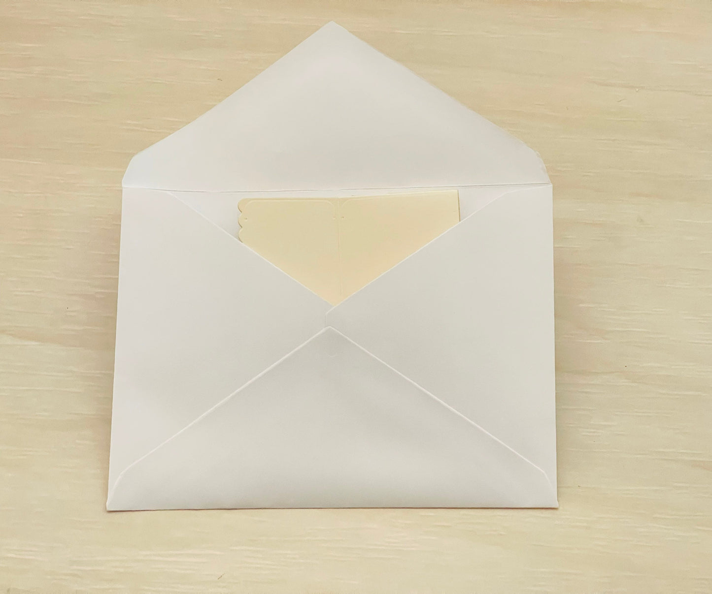 White envelope with a beige interior on a wooden surface