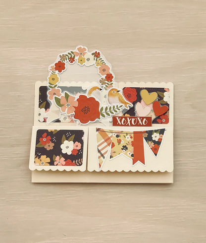 Decorative card with floral and nature-themed designs on a wooden surface