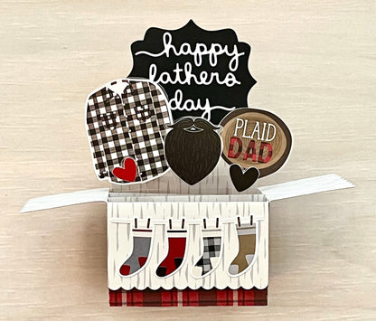 Pop-up card with 'Happy Father's Day' and 'Plaid Dad' text on a wooden surface