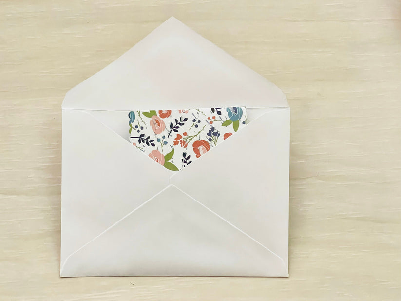 Floral-patterned paper inside a white envelope on a wooden surface