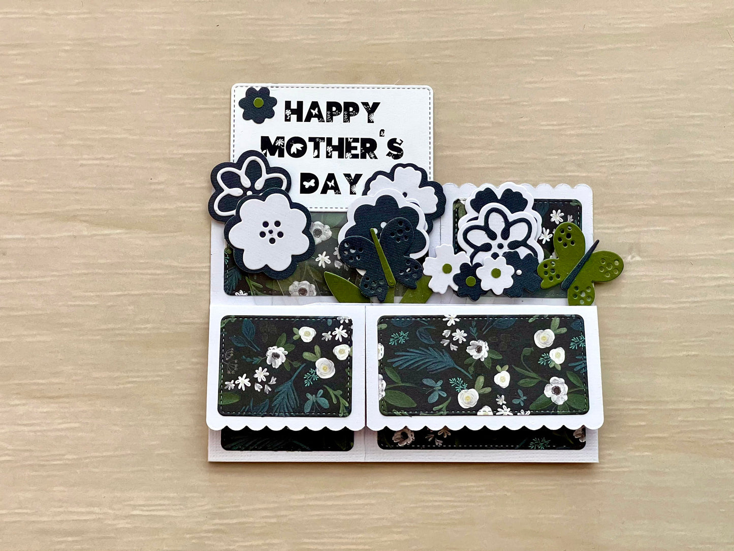 Card with 'Happy Mother's Day' text and floral designs on a wooden surface