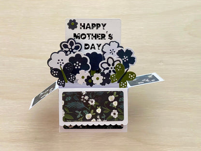 Pop-up card with 'Happy Mother's Day' text and floral designs on a wooden surface