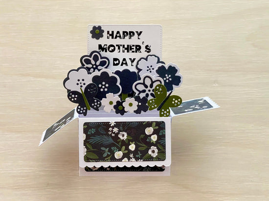 Pop-up card with 'Happy Mother's Day' text and floral designs on a wooden surface