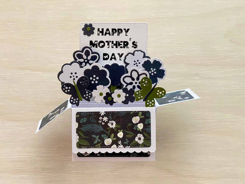 Pop-up card with 'Happy Mother's Day' text and floral designs on a wooden surface