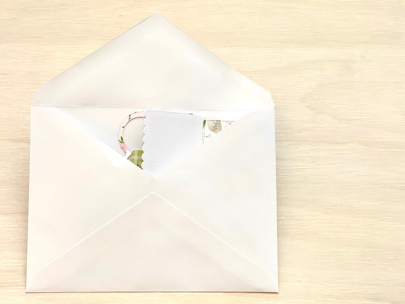 White envelope with a floral card on a beige background