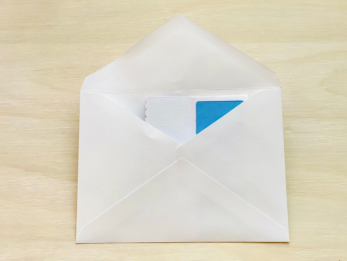 White envelope with a blue card on a wooden surface