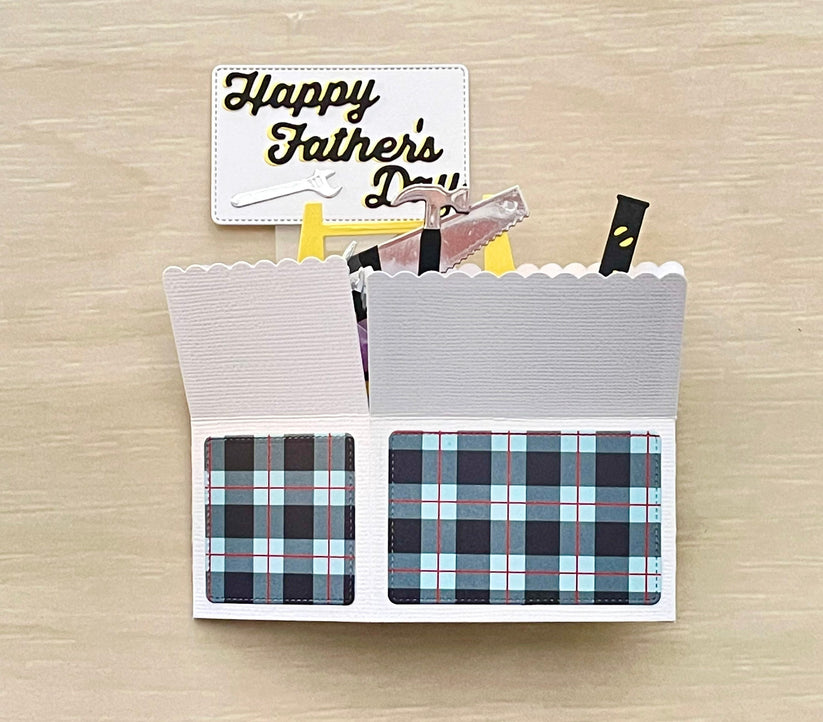 Plaid card with a small tool and 'Happy Father's Day' card on a wooden surface