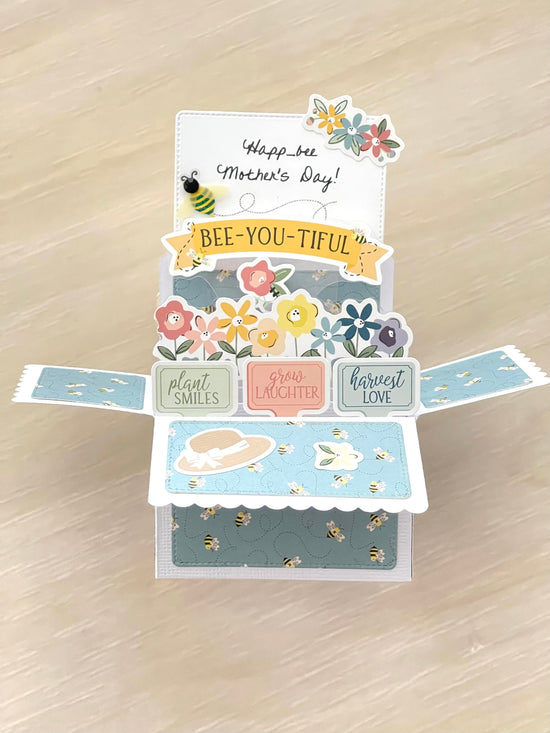 Pop-up card with Mother's Day messages and floral designs on a wooden surface