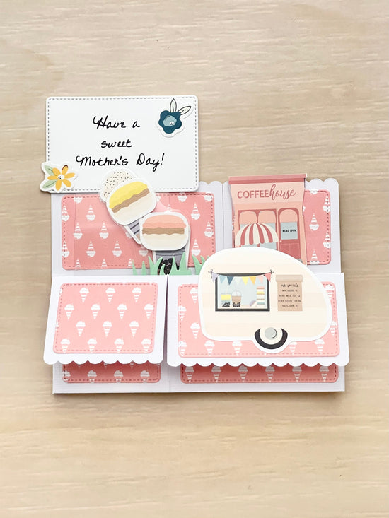 Card with a coffeehouse design and 'Have a sweet Mother's Day!' message on a wooden surface.