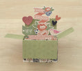 Decorative box pop-up card with floral patterns and text on a wooden surface