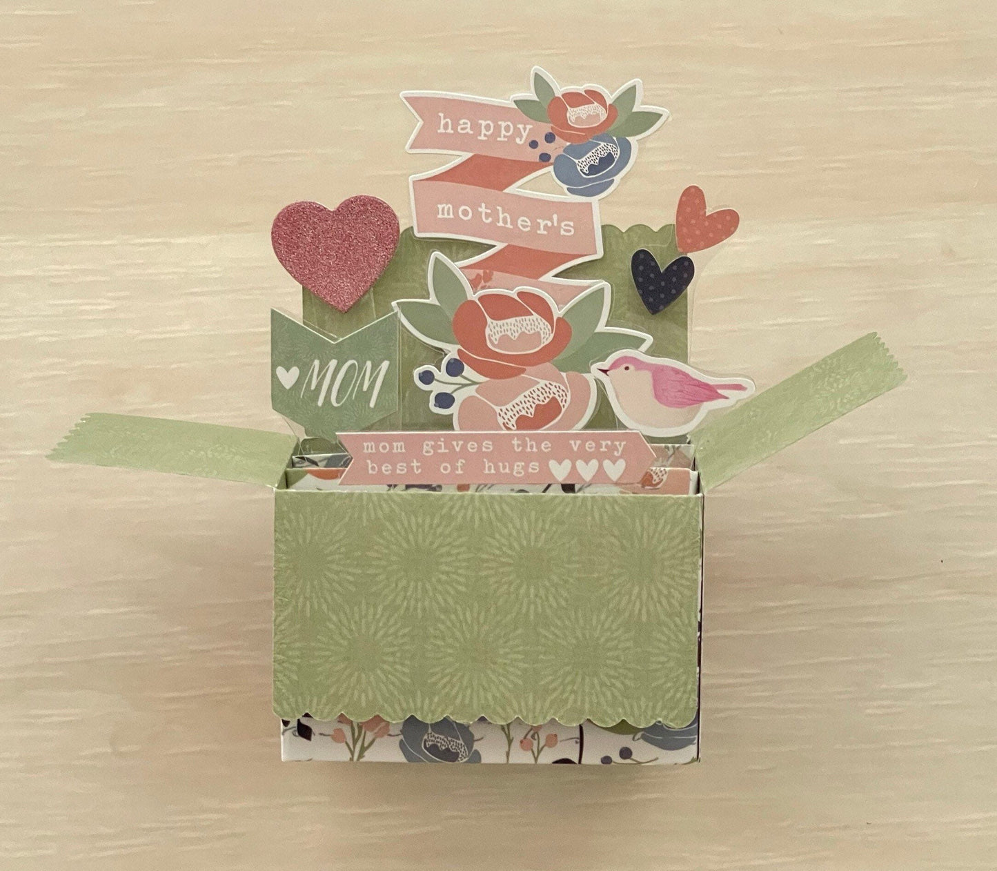 Decorative box pop-up card with floral patterns and text on a wooden surface