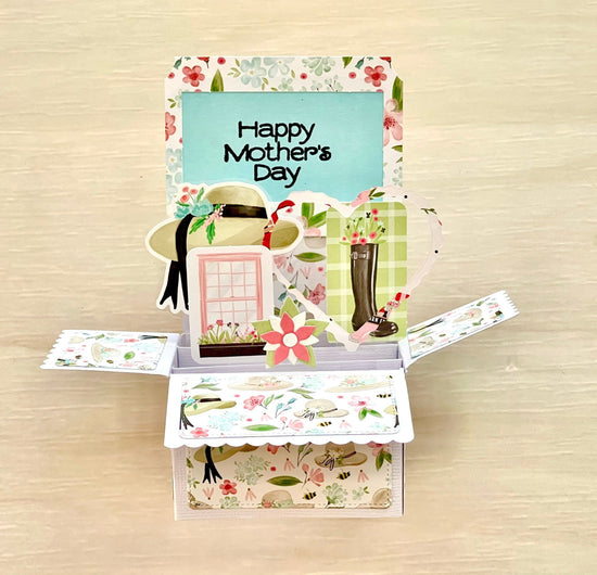 Open Mother's Day pop-up card with floral design and 'Happy Mother's Day' text on a wooden surface.